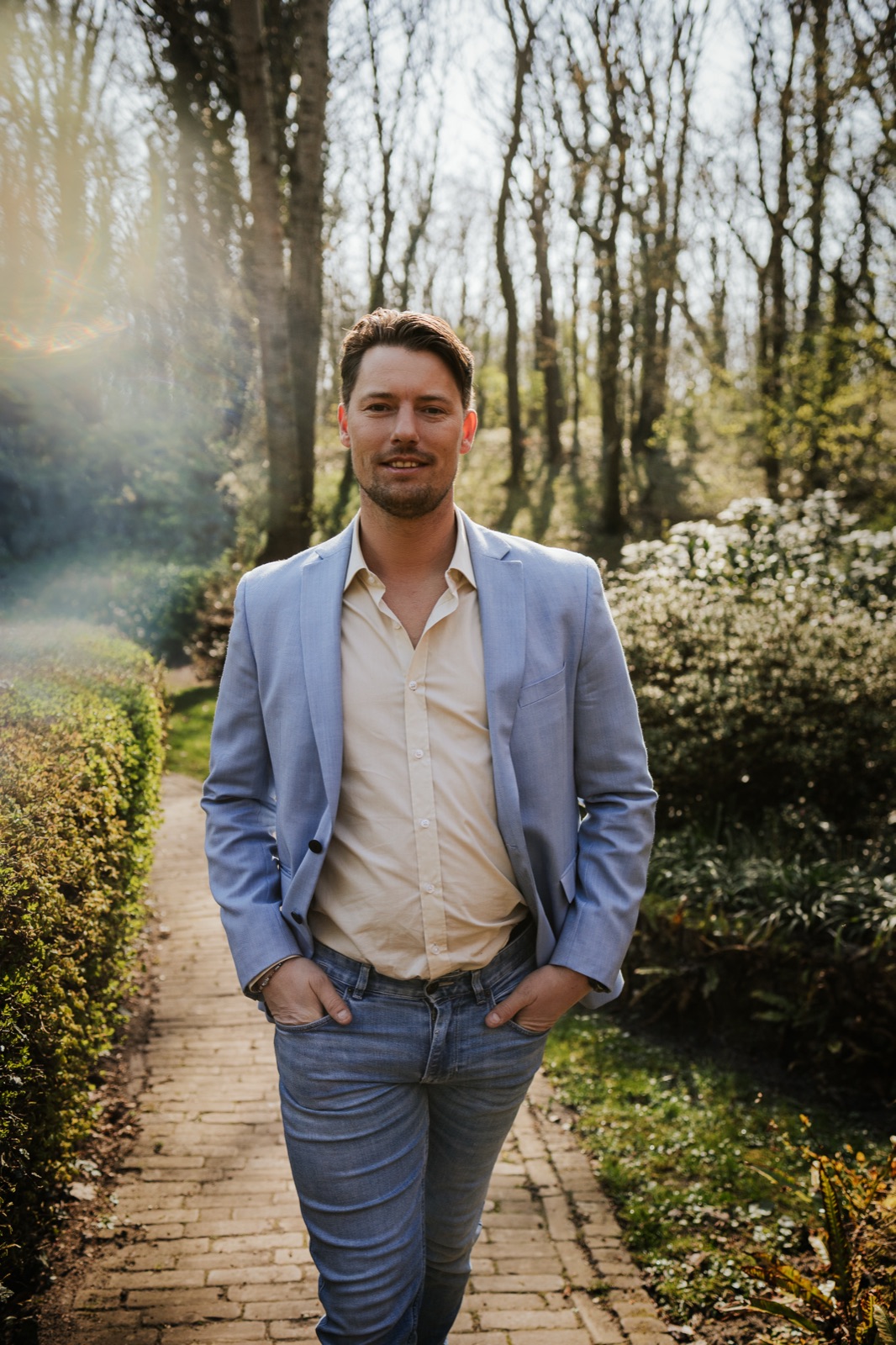 Gijs van Marion, lachend, in blauw colbert op een wandelpad