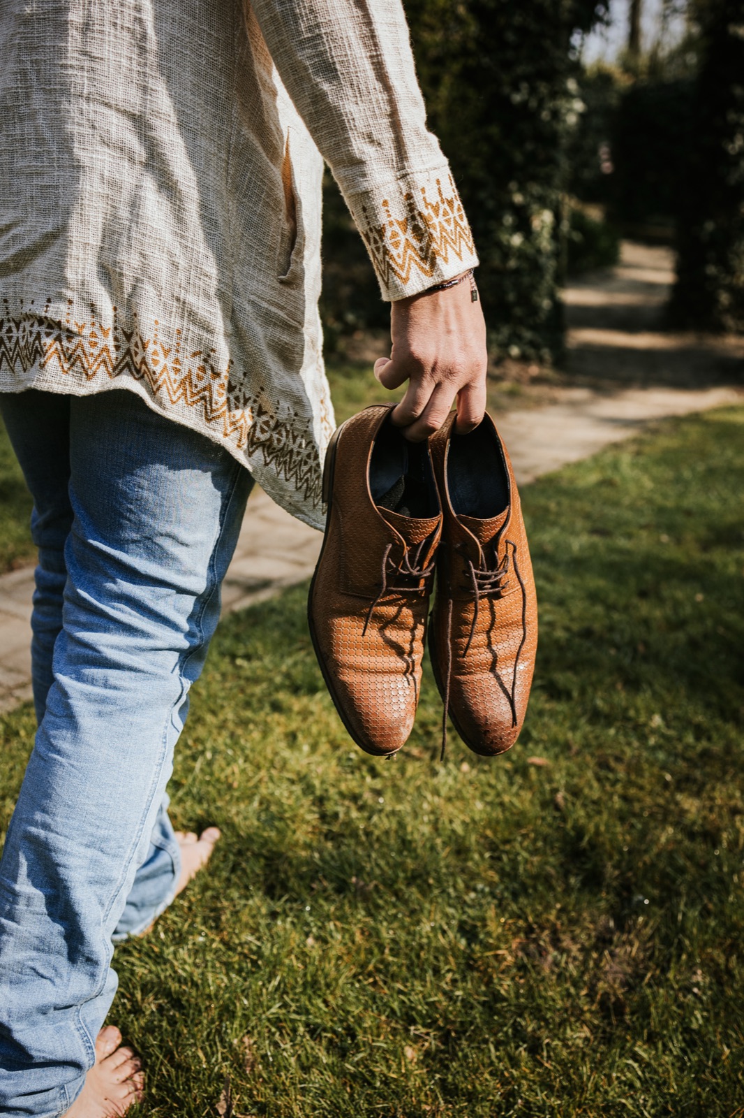 Gijs loopt op blote voeten door het gras, zijn schoenen in de hand